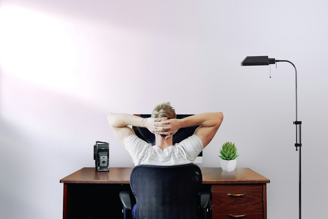 Person tar en paus och sträcker sig vid ett skrivbord