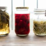 Tre glasburkar med gurkor, rödbetor och strimlad fermenterad kål