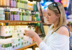 Young woman choosing cosmetic cream in beauty shop.
